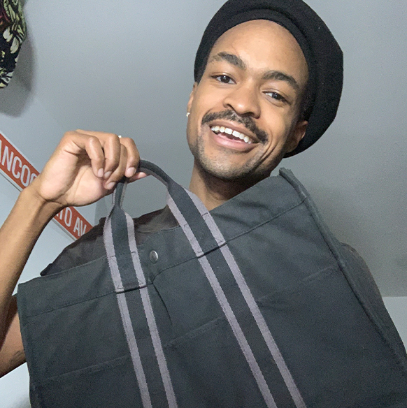 Stylist Ian Bradley holds up a grey tote bag