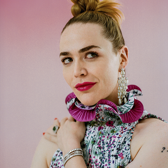 For pride prom, Willie Norris wears pearl and diamond chandelier earrings, a sleeveless, ruffle-neck printed and magenta dress, an emerald and diamond ring, and diamond bracelets.